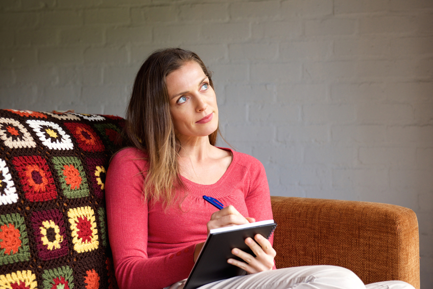 Woman thinking and taking notes in book